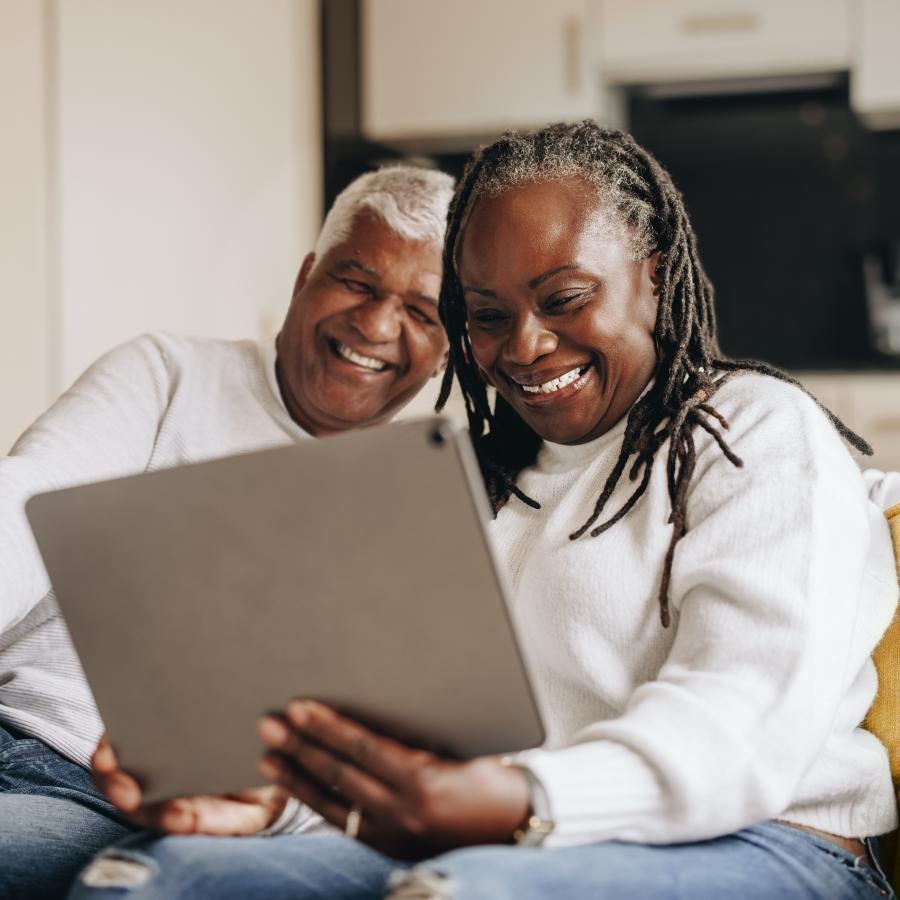 a man and a woman sitting on a couch and looking at a tablet